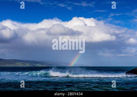 Apollo Bay con la pioggia che si avvicina causando la formazione di un piccolo arcobaleno sull'acqua. Victoria, Australia Foto Stock