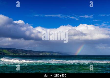 Apollo Bay con la pioggia che si avvicina causando la formazione di un piccolo arcobaleno sull'acqua. Victoria, Australia Foto Stock