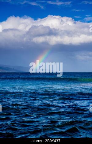 Apollo Bay con la pioggia che si avvicina causando la formazione di un piccolo arcobaleno sull'acqua. Victoria, Australia Foto Stock