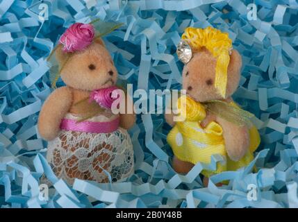 Due orsi in miniatura in panni da festa. Cappelli, gioielli, abiti, nastri decorano i loro piccoli corpi sfumati. Foto Stock