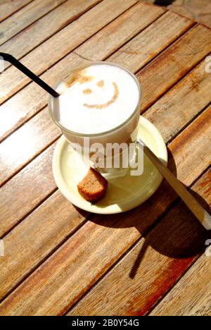 Cafe con leche, latte macchiato con faccina sorridente su un tavolo di legno, Cala Rajada, Mallorca, Spagna Foto Stock