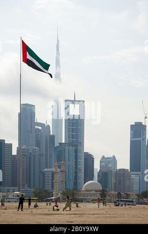 Gli uomini giocano a cricket di fronte allo skyline di Dubai, Emirati Arabi Uniti, Foto Stock