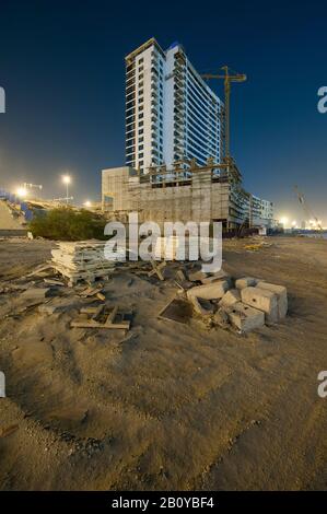 Costruzione di un alto edificio di Sports City di notte, Dubai, Emirati Arabi Uniti, Foto Stock