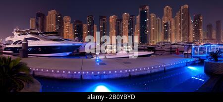 Barche sul molo del Marina Yacht Club con Jumeirah Beach Residences (JBR) di notte, New Dubai, Emirati Arabi Uniti, Foto Stock