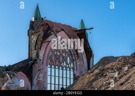 Le rovine di una grande chiesa gotica. Rimane solo una parete, ha una grande finestra con vetrate sulla parte superiore. Grande mucchio di macerie davanti. Soleggiato d Foto Stock