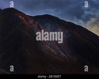 L'ultima sera la luce colpisce una roccia nelle Highlands scozzesi, Glen Coe, Scozia Foto Stock