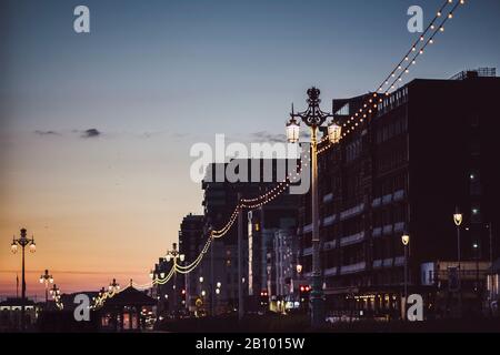 Strada con lanterne sul lungomare al crepuscolo, Brighton, Inghilterra Foto Stock