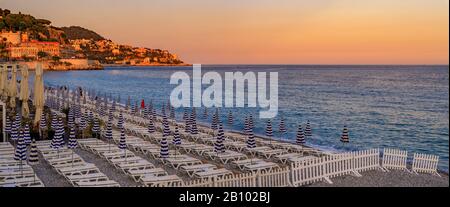 Tramonto sulla spiaggia dalla famosa Promenade des Anglais con sdraio, ombrelloni e il Mar Mediterraneo sullo sfondo a Nizza, nel sud della Francia Foto Stock