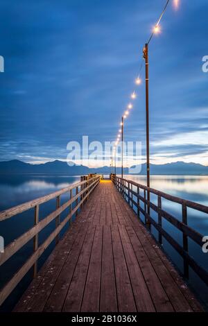 Il vaporetto attracca al Chiemsee con luci all'ora blu, Seebruck, Baviera, Germania Foto Stock