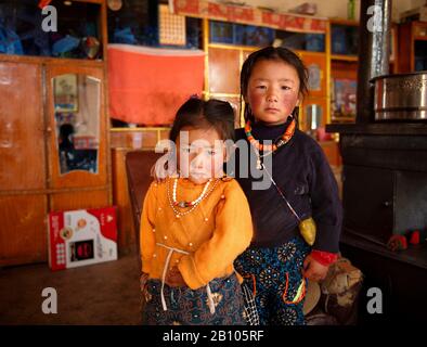 I bambini tibetani si divertono a vicenda. Da un'età molto precoce imparano che stare insieme e stare a vicenda è un valore molto importante nella vita. Altopiano tibetano remoto Foto Stock