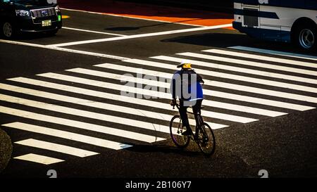 Una bicicletta a Tokyo velocità attraverso l'attraversamento pedonale zebra. Foto Stock