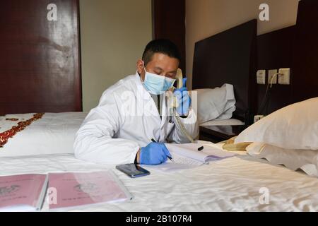 (200222) -- HEFEI, 22 febbraio 2020 (Xinhua) -- l'operatore sanitario li Hao della stazione sanitaria di Yonghe nella Comunità di Changning chiede di conoscere le condizioni di salute dei membri del personale in quarantena a Hefei, nella provincia dell'Anhui nella Cina orientale, 21 febbraio 2020. Trentacinque membri dello staff dell'Anhui Branch of China Construction Eighth Engineering Division Corp. Ltd., che hanno partecipato alla costruzione del improvvisato ospedale Leishenshan per nuovi pazienti affetti da polmonite da coronavirus a Wuhan, sono tornati recentemente a Hefei. Sono ora in quarantena per l'osservazione medica in un hotel a Hefei. Ognuna di esse dispone di una camera separata Foto Stock