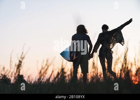 Buona coppia giovane tenuta mentre si sta in piedi sulla spiaggia, tenendo surf board Foto Stock