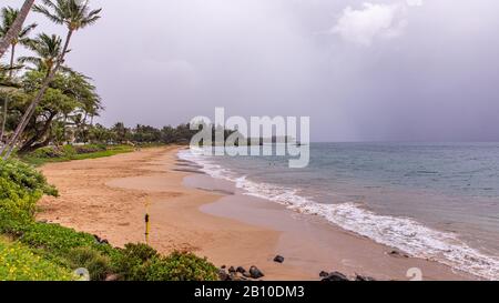 La spiaggia vuota del parco Kamaole Beach III. Nessuna gente la spiaggia a causa di una tempesta tropicale Erick avvertimento. Il cielo è chiuso con nuvole piovose. Foto Stock