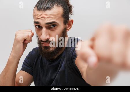 Immagine di giovane sportivo bruna che indossa la boxe con tuta a macchina fotografica isolata su sfondo bianco Foto Stock