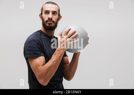 Immagine di giovane sportivo bruna che indossa tuta facendo allenamento con palla fitness isolato su sfondo bianco Foto Stock