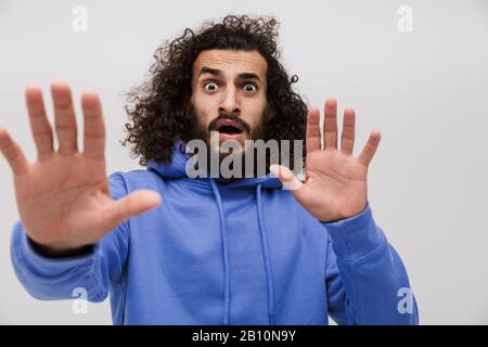 Immagine di un uomo shockato in una felpa casual che esprime meraviglia alla macchina fotografica isolata su sfondo bianco Foto Stock