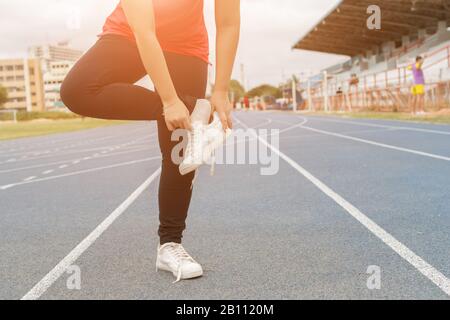 Corridore giovane donna che indossa le scarpe prima della corsa - concetto di workout Foto Stock