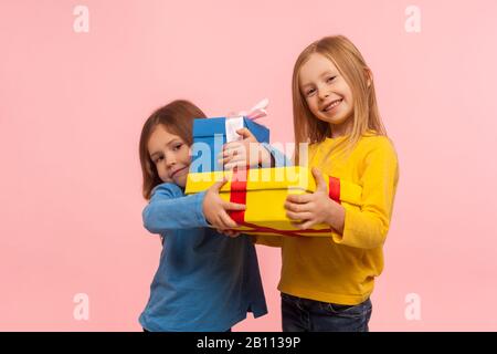 Regalo di vacanza per bambini. Due ragazze piccole felici che tengono insieme i regali e sorridono alla macchina fotografica, bambini che abbracciano i regali di natale, surpris di compleanno Foto Stock