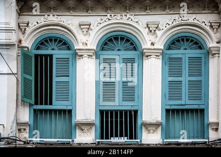 Persiane in legno sulle finestre in diverse forme. Edifici colorati nella vecchia città di Phuket in Thailandia. Stile sino Portoghese. Foto Stock