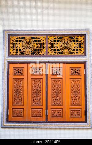 Persiane in legno sulle finestre in diverse forme. Edifici colorati nella vecchia città di Phuket in Thailandia. Stile sino Portoghese. Foto Stock