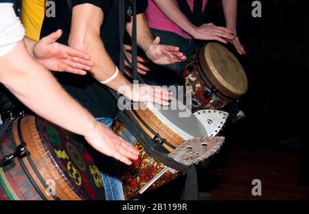 Le persone giocano le mani sulla batteria etnica al buio Foto Stock