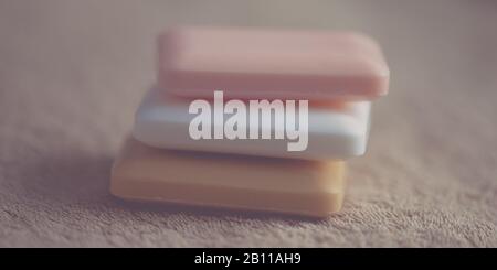 Stack di tre barre di sapone diversi colori su un asciugamano marrone Foto Stock