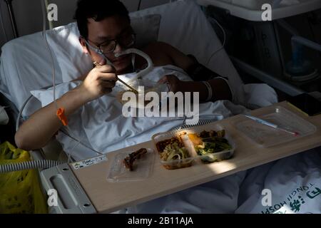 Un paziente cinese mangia il pranzo nel reparto di isolamento in un ospedale nella città di Wuhan, la provincia centrale dell'Hubei in Cina il 22nd febbraio 2020. Foto Stock