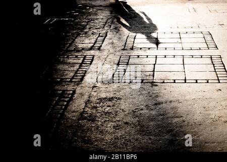 Silhouette sfumata sul marciapiede della città di misterioso uomo che cammina da solo Foto Stock