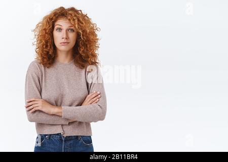 Scettico, insicuro caucasico redhead curly donna guardando con incredulità e giudizio, non comprarlo, pensare qualcuno sdraiato, croce braccia petto in chiuso Foto Stock