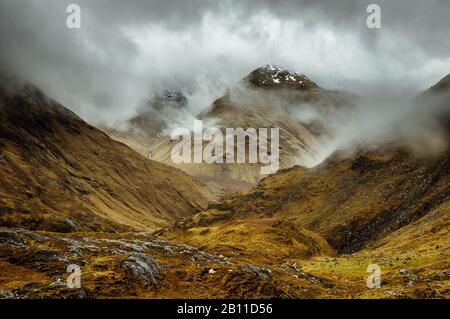 Scendendo verso ovest dal passo tra Gleann Lichd e Glen Affric, Scozia, come un picco è rivelato brevemente attraverso le nuvole Foto Stock