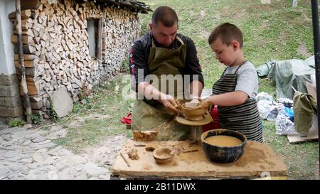 Museo Etnografico All'Aperto 'Etar' - Gabrovo, Bulgaria. 06 settembre 2019 - XVII Fiera Internazionale dell'Artigianato tradizionale. Il maestro insegna un chil Foto Stock