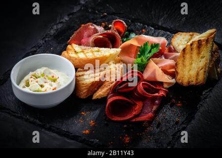 piatto di specialità di carne disposto su uno sfondo nero testurizzato Foto Stock