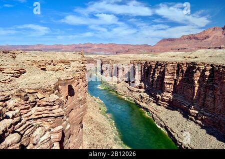 Una vista del possente fiume Colorado che si fa strada attraverso la roccia rossa del Grand Canyon. Piccole figure in lontananza sono il rafting sulle rapide. Foto Stock