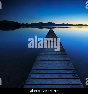 Dopo il tramonto a Chiemsee, attracco per barche con le Alpi Chiemgau, Baviera, Germania Foto Stock