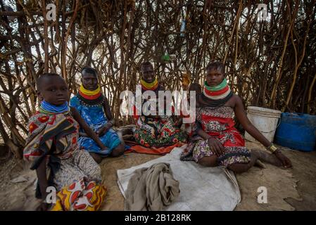 Le donne turkane indossano le loro tradizionali collane, all'interno della loro capanna fatta di rami e foglie. Kenya Foto Stock