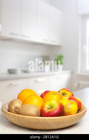 Primo piano di frutta in una ciotola di legno in una cucina bianca Foto Stock