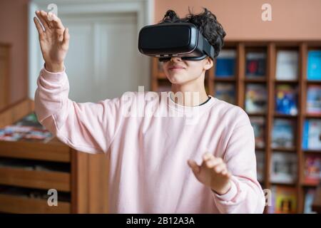 Teenager in casualwear guardando la mostra virtuale di fronte a lui Foto Stock