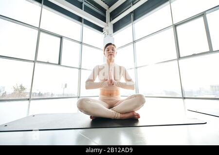 Ragazza serena in attività seduta in posa di lotus durante l'esercizio di relax Foto Stock