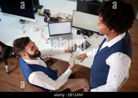due colleghi , multietnici, in ufficio che hanno scambio di denaro. business, contanti, tangente, corruzione, prestito, dare, prendere, concetto Foto Stock