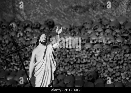 Statua di Gesù di fronte ai teschi delle vittime - peste del 1656 e epidemia di colera nel 1836, Cimitero delle Fontanelle, quartiere Sanità Napoli Italia Foto Stock