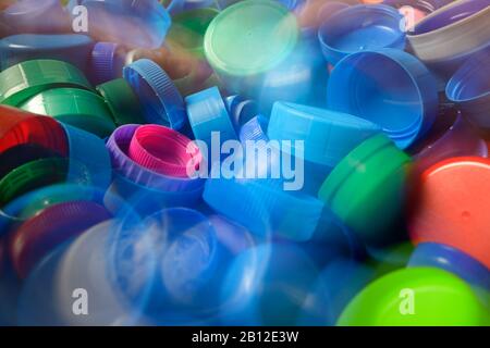 Capsule in plastica per flaconi di varie dimensioni e colore che cadono nel cestello. Foto Stock