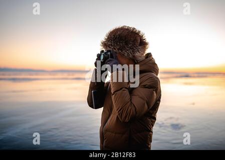 Fotografo in piedi sul lago ghiacciato, il lago Baikal, Siberia, Russia Foto Stock