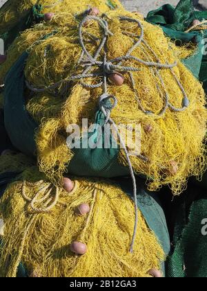 Reti da pesca gialle con galleggianti di colore rosso scuro in sacchi verdi sulla riva di Agios Georgios Lichados, Evia, Grecia Foto Stock