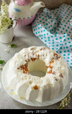 Dessert di Pannacotta. Cottage souffle di formaggio panna cotta con albicocche e decorazioni di cocco su una pietra o ardesia su un piano di lavoro leggero. Spazio di copia. Foto Stock