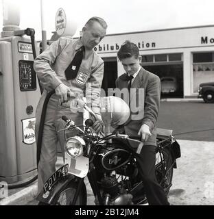 1950s, storico, un giovane motociclista maschile parcheggiato dalle pompe di carburante in un garage che riceve carburante e olio per la sua moto Excelsior da un addetto al piazzale uniformato, Londra, Inghilterra, Regno Unito. Con l'aumento dell'automobilismo nel Regno Unito dopo la guerra, sono stati aperti garage più grandi o stazioni di servizio che offrono una gamma di servizi relativi al motore, tra cui assistenti di piazzale presidiati. Con sede a Coventry, in Inghilterra, Excelsior fu il primo produttore britannico di moto, producendo la propria bicicletta motoria nel 1896. Foto Stock