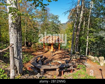 Luogo pic-nic con gazebo in legno, tavoli e panchine in legno tra gli alberi della foresta e le montagne Foto Stock