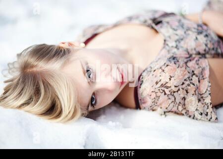 Giovane donna sdraiata sulla neve, ritratto Foto Stock