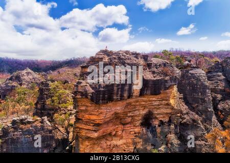 Ripide scogliere di arenaria in Blue Mountains of Australia. La ragazza solitaria siede sulla parte superiore. Foto Stock