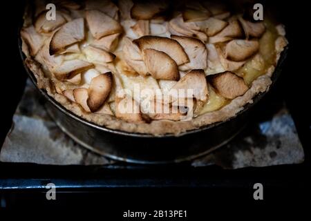 Home cottura Tsvetaevsky apple aspic di aprire la torta in forno, close-up. Concetto di cottura. Cena in famiglia. Sfondo scuro Foto Stock